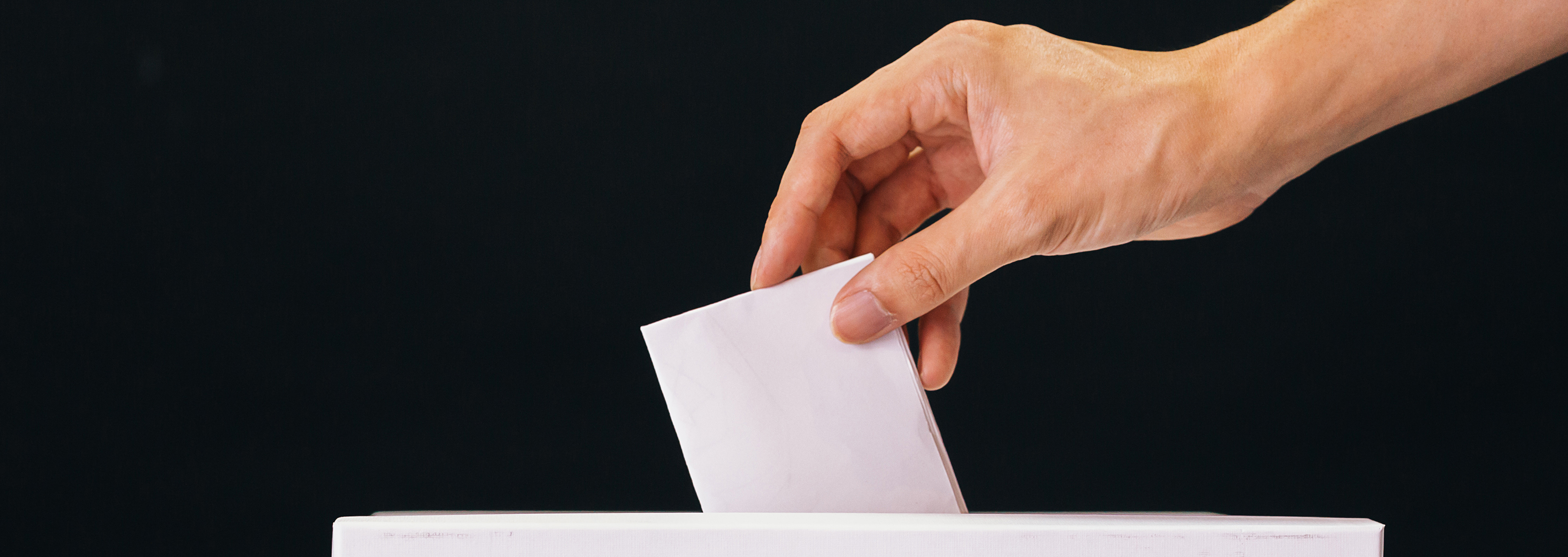 Hand Placing a piece of paper into a ballot box
