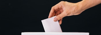 Hand Placing a piece of paper into a ballot box