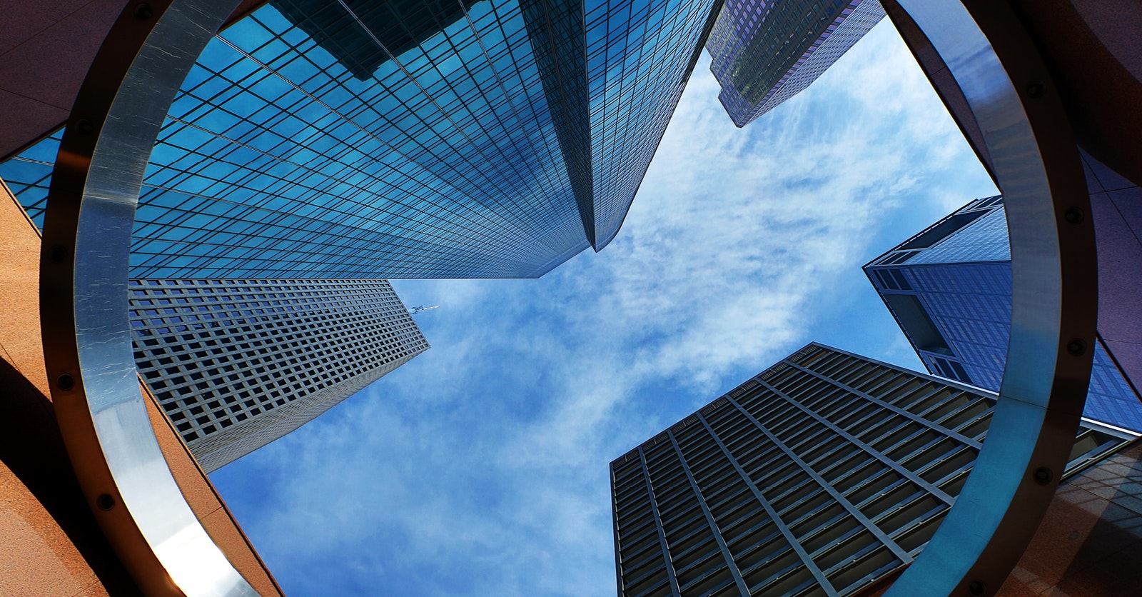View from the ground looking up at the sky with buildings surrounding the blue sky