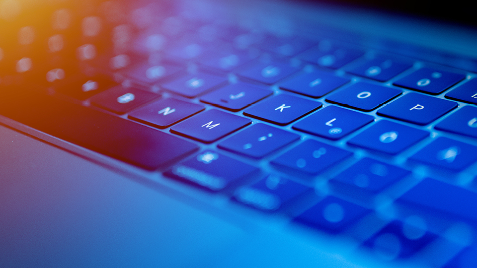 Keyboard with blue lighting, photographed from the side on a diagonal