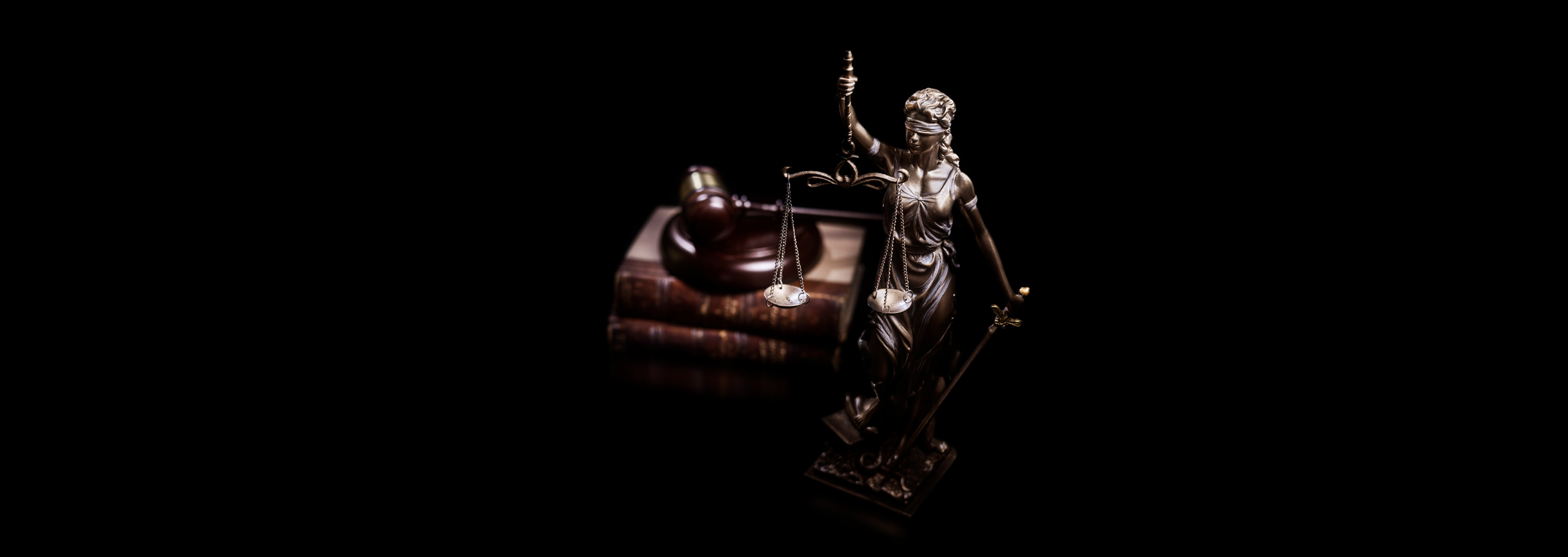 A statue of a woman holding a chain level distributer in front of books and a gavel